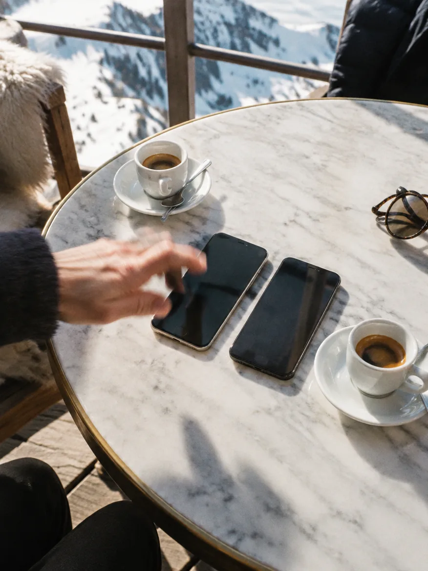 Eine Hand greift nach einem von zwei Telefonen auf einem Marmortisch.