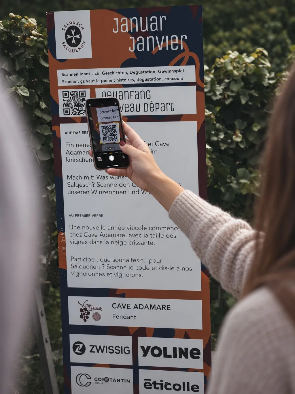 Eine Hand scannt mit dem Telefon den QR-Code auf einer Stele.