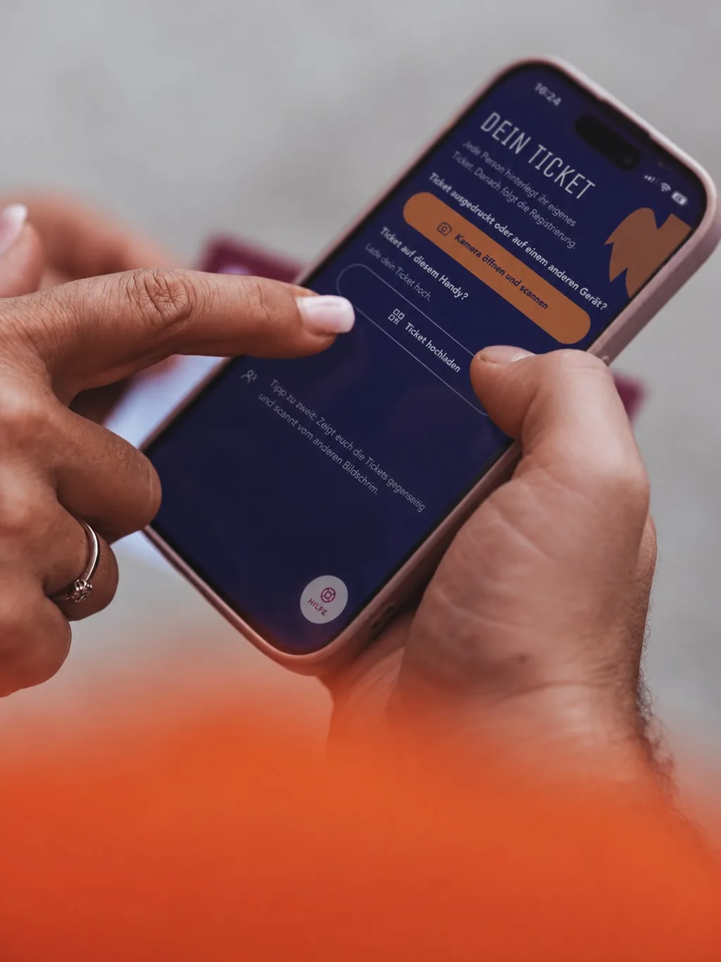 Eine Person hält ein Telefon mit digitalem Ticket, eine zweite tippt darauf.